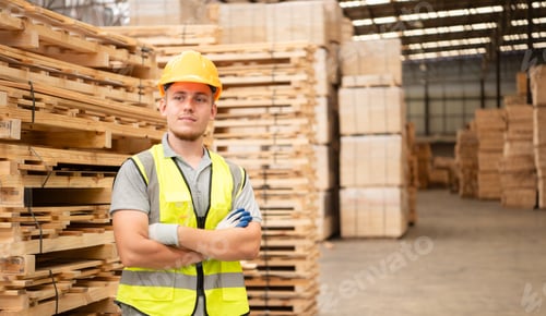Preview: Portrait of warehouse worker checking stock of wooden pallets in storage warehouse.