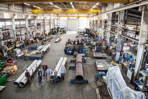 Preview: Mixed race team of workers and management people in a large sheet metal factory