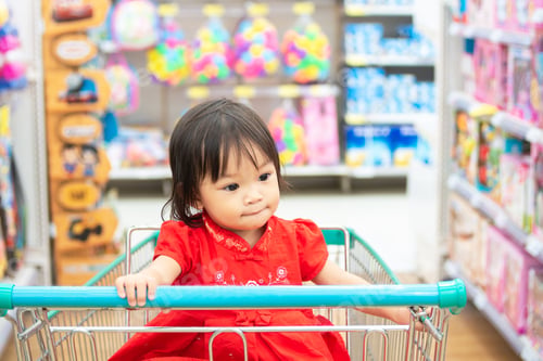 Preview: Happy Asian child girl sitting in a cart shopping at the supermarket.