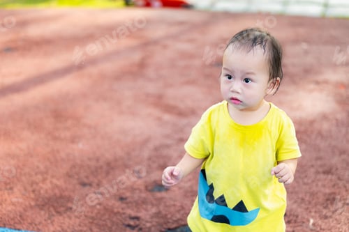 Preview: Portrait of cute Asian baby boy is walking at the playground, child looks at something.