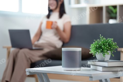 Preview: Smart Home. Woman enjoying coffee while using laptop near smart speaker.