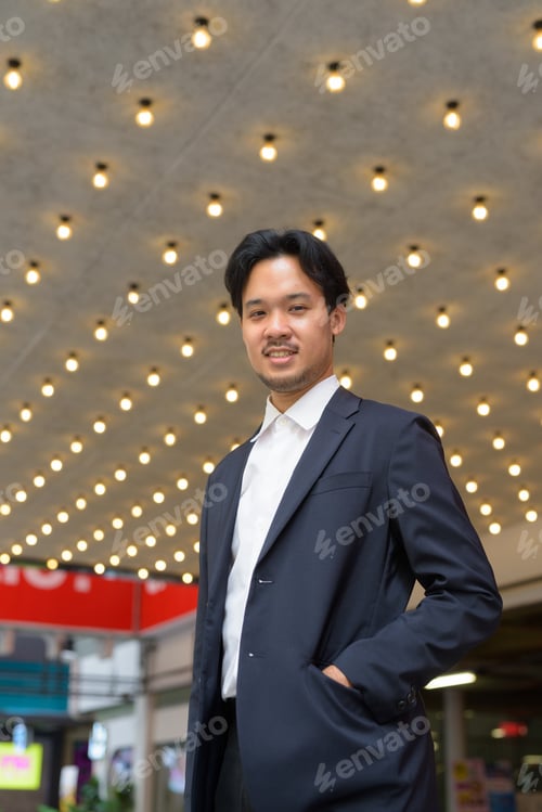 Preview: Portrait of Asian businessman smiling outdoors in the city