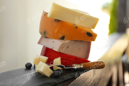 Preview: Different types of delicious cheeses and fork on wooden railing outdoors, closeup