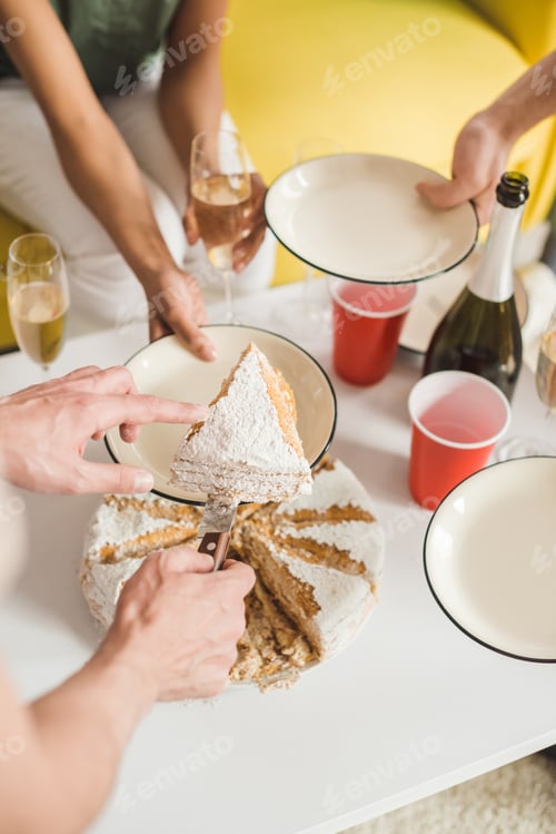 Preview: Close-up view of man cutting birthday cake at party