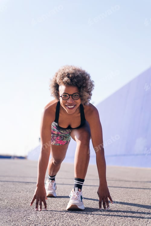 Preview: sportswoman smiling in position to start a race