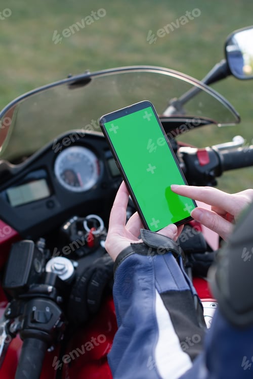 Preview: girl motobiker uses a mobile phone with a green screen for navigation and rides a motorcycle,