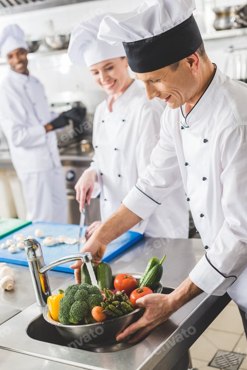 Preview: smiling chef washing vegetables at restaurant kitchen