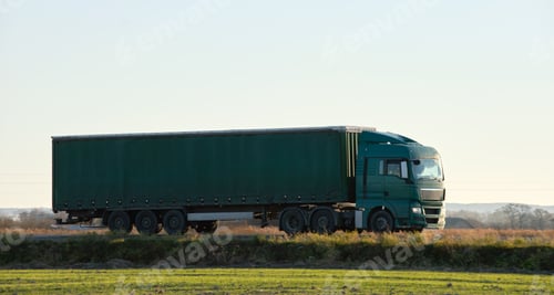 Preview: Semi-truck with cargo trailer driving on highway hauling goods in evening