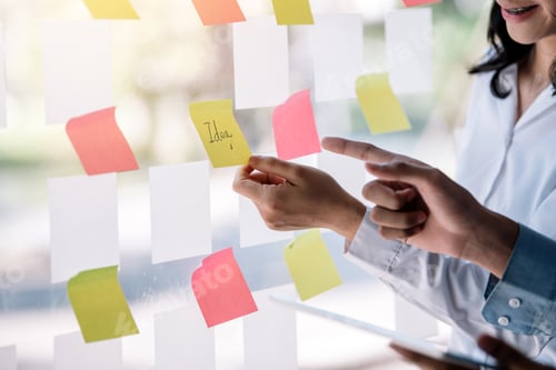 Preview: Group of business people meeting and planning sticking sticky note on the glass wall in the office.