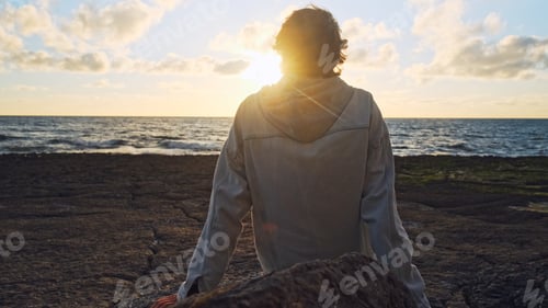 Preview: Man on a beach is looking distance during beautiful summer sunset.
