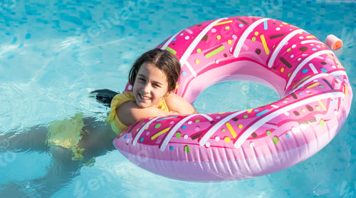 Preview: girl plays an inflatable ring is in swimming pool in the garden
