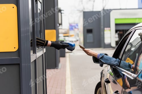 Preview: partial view of cashier in latex glove holding payment terminal near woman in car