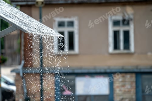 Preview: Rain dripping from awning in front of building. Background with selective focus and copy space