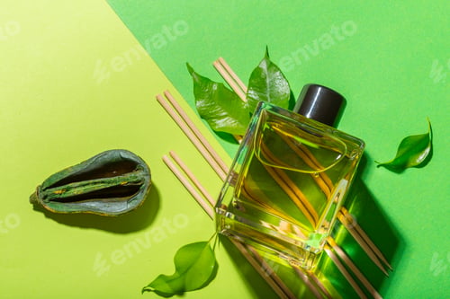 Preview: Elegant perfume bottle surrounded by green leaves and sticks on a vibrant backdrop