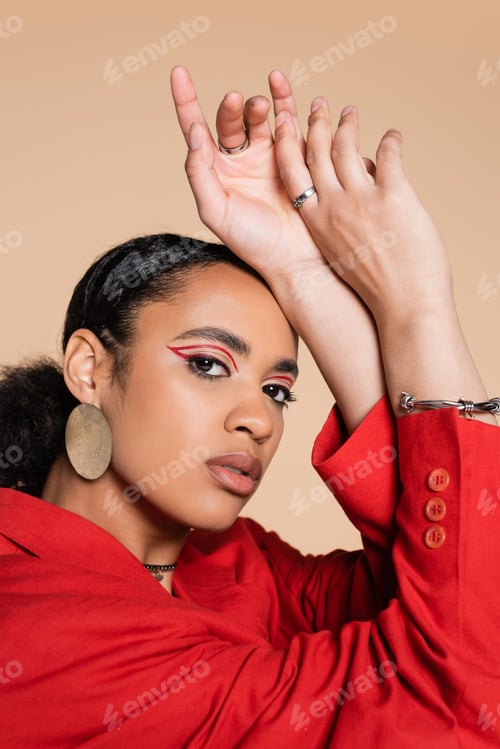 Preview: portrait of stylish african american woman in bright red blazer gesturing while looking at camera