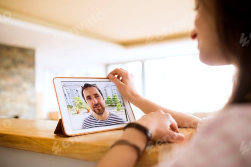 Preview: Young woman using tablet for video chat at home