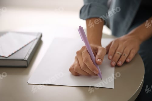 Preview: Woman writing letter at table indoors, closeup