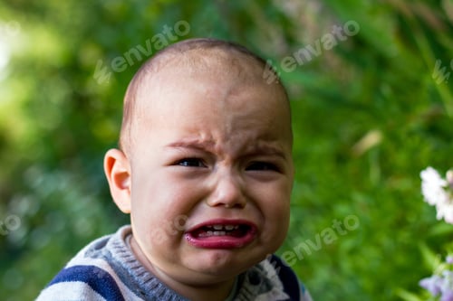 Preview: Cute little baby boy outdoors. Crying unhappy baby at green garden.