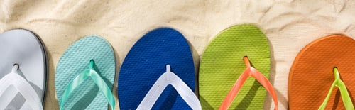 Preview: panoramic shot of white, turquoise, green and blue flip flops on sand