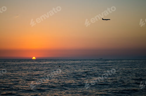 Preview: Airplane at sunset over tranquil ocean horizon