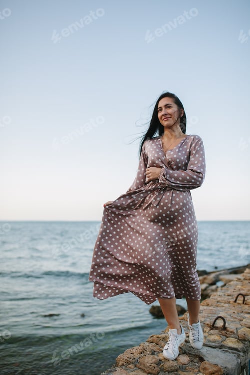 Preview: Women in a sundress on the sand on the beach near the ocean