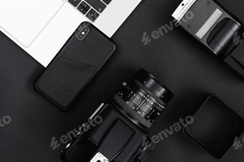 Preview: Top view of a camera and flash with a phone on a laptop on a dark surface