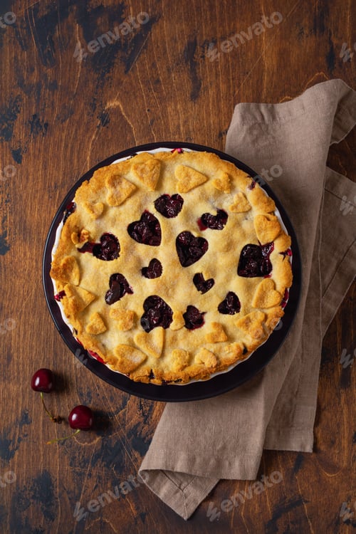 Preview: Tasty homemade cherry pie with hearts on wooden background. Valentines Day baked goods. Top view