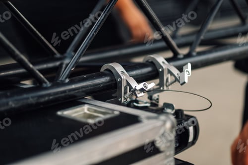 Preview: Stage hand setting up truss for concert using steel clamp