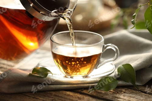 Preview: Pouring tea into cup on wooden table, closeup