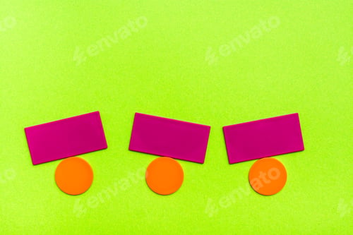 Flat colored shapes - circles and rectangles - simulate balancing on green cardboard.