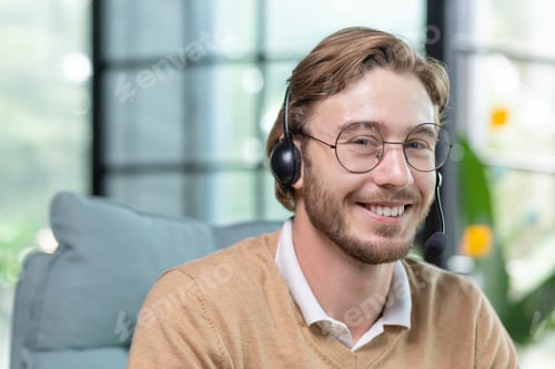 Preview: Portrait of young man with headset for video call inside office, close-up tech support worker in