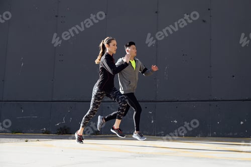Preview: Fit and sporty couple running in the street.