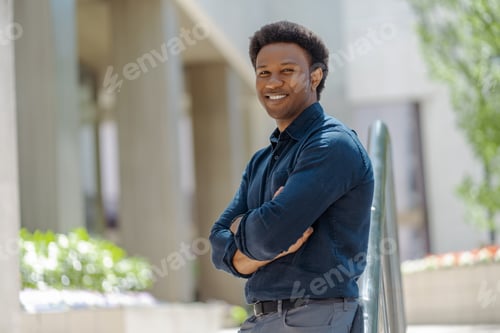 Preview: Smiling handsome african american man with arms crossed looking away outdoors
