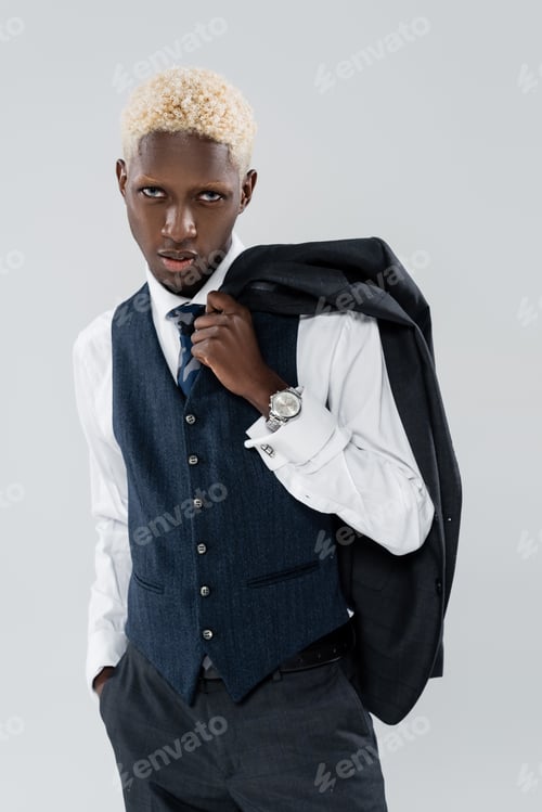 Preview: blonde african american man with blue eyes holding blazer and posing with hand in pocket isolated on