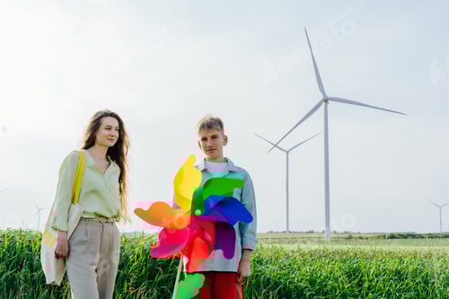 Preview: Young woman and teenage boy with rainbow pinwheel on green field