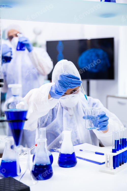 Preview: Chemist holding a pipette with a blue liquid trying to make an experiment