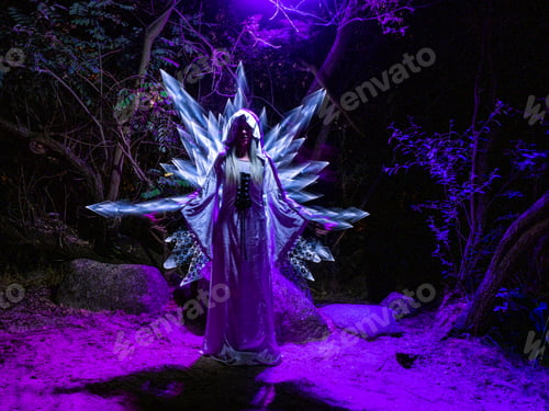 Preview: woman in the woods with swords coming out of her back made with light. Lightpainting technique