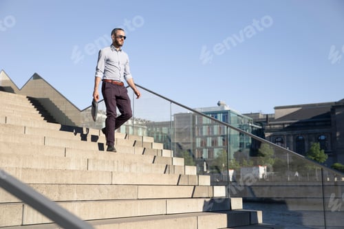 Preview: Businessman wearing sunglasses walking downstairs