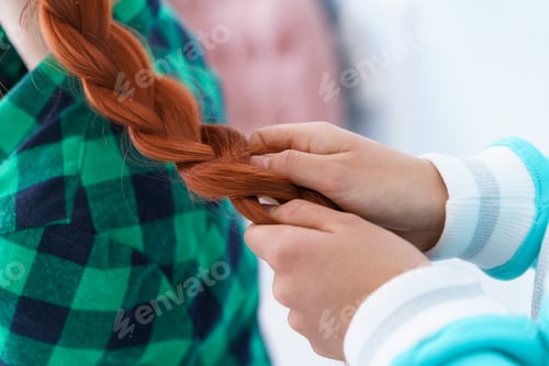Preview: A friend is braiding a braid for a red-haired girl.
