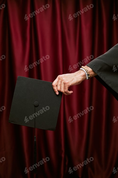 Preview: Young Adult Man Holding Graduation Cap in Photo Booth Setting