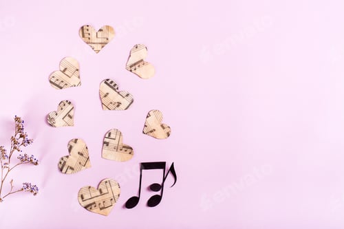 Preview: Paper hearts, notes and dry flowers on a pink background. Love music concept. Top view.