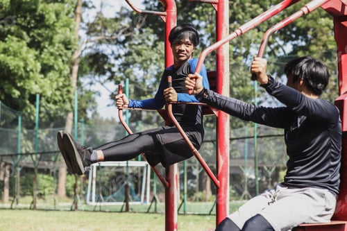 Preview: Young man workout together with friend use fitness equipment outdoor
