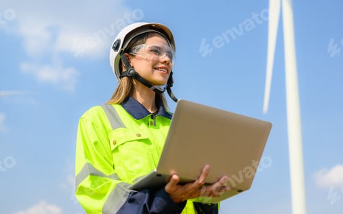 Preview: Happy female engineer technician working outdoor at wind turbine field