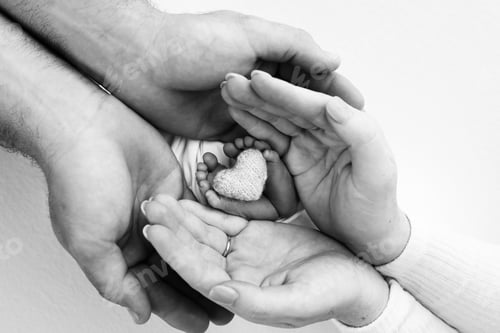 Preview: Children's leg in the hands of mother, father, parents. Feet of a tiny newborn close up.