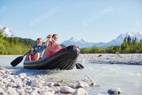 Preview: Couple using paddles to steer dinghy on water, Wallgau, Bavaria, germany