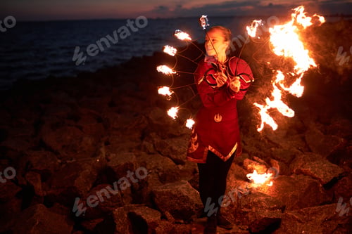 Preview: Woman dancing with fire fans outdoors