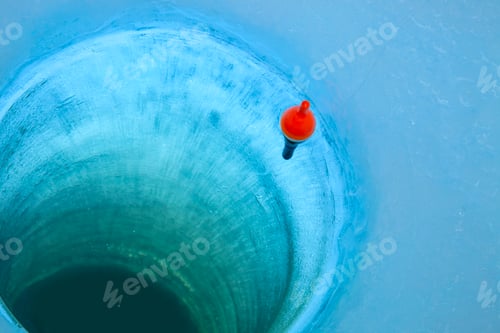 Preview: Red bobber and fishing line in an ice fishing hole in a Minnesota lake