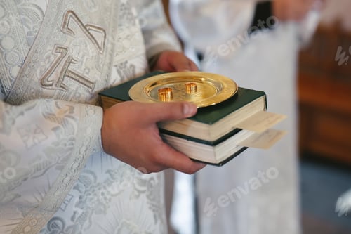 Preview: Close-up photo of a wedding ring held by a priest in a church before the wedding ceremony