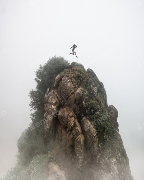 Preview: Fantasy concept - a person jumping over a high rocky cliff with a blurred foggy white background