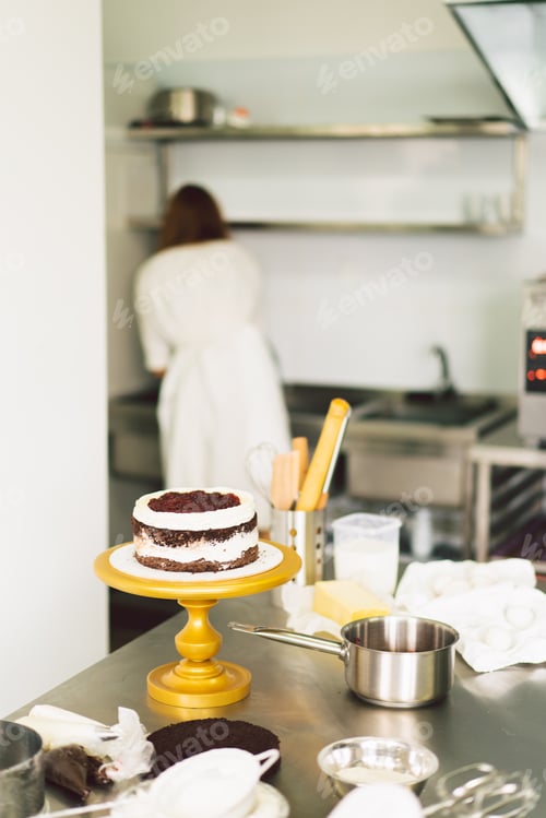 Preview: Confectioner girl is preparing a cake biscuit with white cream and chocolate. Cooking cakes.